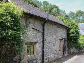 A stone building with windows and vegetation surrounding it at The Mill Barn in Lustleigh