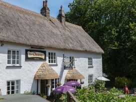 A public house building with a thatched roof and outdoor seating at The Cleave in Lustleigh
