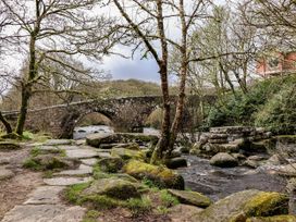 A stone bridge over a river with trees and stones at The Mill Barn in Lustleigh