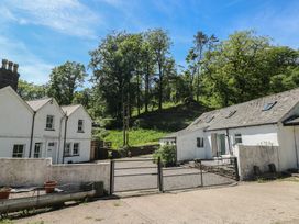 An outdoor view of houses with a gate and trees at Daffodil Cottage in Blaencwm near Treorchy