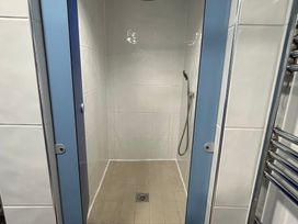 A shower enclosure with tiles and a showerhead at Cosy Cocoon near Rillington