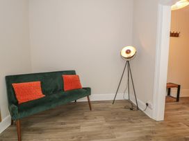 A living room with a green sofa and a floor lamp at Llety Cllyd in Barmouth