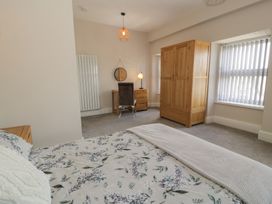 A bedroom with a bed, wardrobe, desk, and chair at Llety Cllyd in Barmouth