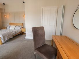A bedroom featuring a bed, desk, chair, and mirror at Llety Cllyd in Barmouth