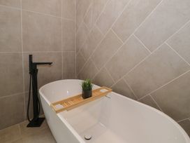 A bathroom featuring a bathtub with a wooden tray and plant at Llety Cllyd in Barmouth