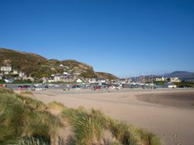 A beach with cars parked and houses on the hillside at Llety Cllyd in Barmouth