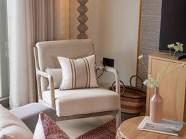 A living room with an armchair and a vase on a side table at Clifftop House Hot Tub in St Ives
