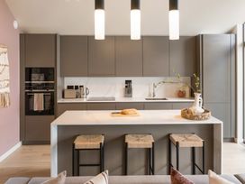 A kitchen with cabinets, island, sink, and stools at Clifftop House Hot Tub, St Ives