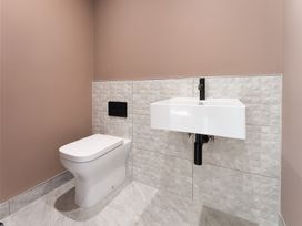 A bathroom with a toilet and a wall-mounted sink at Clifftop House Hot Tub in St Ives