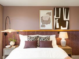 A bedroom with a bed, bedside table, lamp, and art at Clifftop House Hot Tub, St Ives
