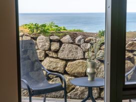 An outdoor patio with chairs and a table overlooking the ocean at tbc St. Ives