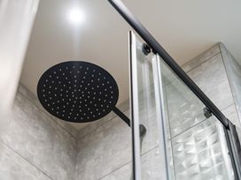 A shower area with a round shower head and glass door at tbc in St. Ives