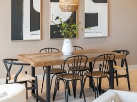 A dining room with a wooden table and chairs including a vase and artwork at tbc in St. Ives