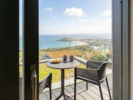 A balcony with a table and chairs overlooking the sea at Hidden 9 – Grand Bay Suite Hot Tub, St Ive