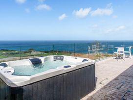 An outdoor space with a hot tub and chairs overlooking the ocean at tbc in St. Ives