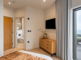 A bedroom with a dresser and television at tbc in St. Ives