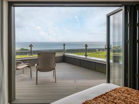 A bedroom with a view of the ocean and a chair at tbc in St. Ives