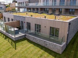 An outdoor view of a modern building with grass roof and glass railings at tbc St. Ives