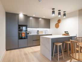 A kitchen with cabinets, an oven, and stools at Hidden 19- Coastal Hot Tub St Ives