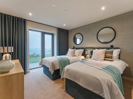 A bedroom with two beds and a sliding door at Hidden 19- Coastal Hot Tub, St Ives
