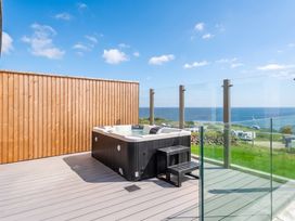 An outdoor area with a hot tub and ocean view at Hidden 19- Coastal Hot Tub St Ives