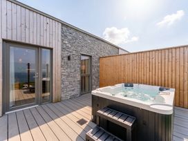 An outdoor area with a hot tub on a wooden deck at Hidden 19- Coastal Hot Tub, St Ives
