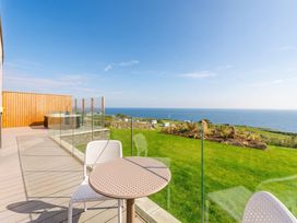 An outdoor area with a table and chairs overlooking the ocean at Hidden 19- Coastal Hot Tub, St Ives