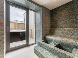 A bathroom with a hot tub and tiled seating area at Hidden 20- Gallery Hot Tub, St Ives