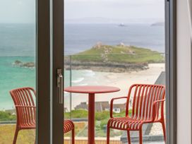 A balcony with a table and chairs overlooking the beach at Hidden 10- Godrevy View, St Ives