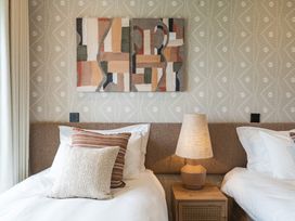A bedroom with two beds and artwork on the wall at Hidden 10- Godrevy View, St Ives