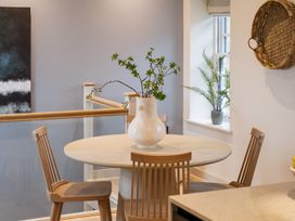 A dining room with a round table and a vase of branches at tbc in St. Ives