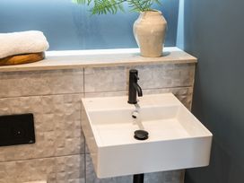 A sink with a faucet and a vase on a shelf at tbc in St. Ives