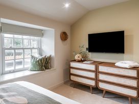A bedroom with a window, cushions, television, and a drawer unit at tbc in St. Ives