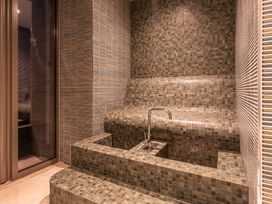 A bathroom with a tiled water feature and bench at Hidden 7- Coastal Loft in St Ives