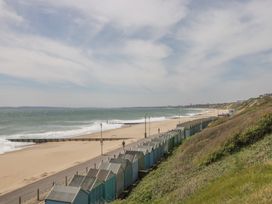 A beach with beach huts and waves at 7 Blue Water in Bournemouth