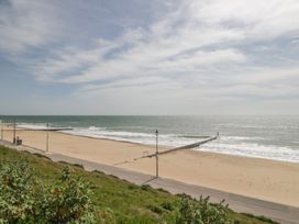 A beach with a pier and pathway at 7 Blue Water in Bournemouth