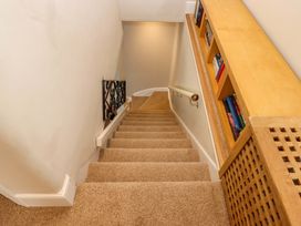 A staircase with a handrail and bookshelf at Kents Cottage in Torquay
