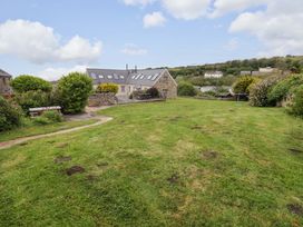 A garden with grass and a stone building at No.8 Millmoor Farm Cottage in Broad Haven