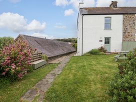 An outdoor view of a house with a path and flower bushes at No.8 Millmoor Farm Cottage in Broad Haven