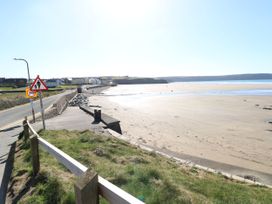 A beach view with road, sign, and houses at No.8 Millmoor Farm Cottage in Broad Haven