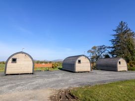 Three wooden pods with a sign in between at Bron Eifion Pod 1 Criccieth