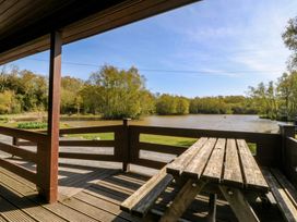 An outdoor seating area overlooking a lake at Lodge 1 - Bron Eifion in Criccieth
