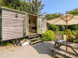 An outdoor seating area with a shepherd hut and table at The Three Spaniels Shepherds Hut Cwrtnewydd near Llanybydder