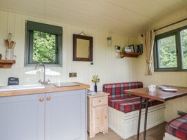 A kitchen with a dining table and seating at The Three Spaniels Shepherds Hut Cwrtnewydd near Llanybydder