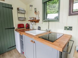 A kitchen with a sink, stove, and refrigerator at The Three Spaniels Shepherds Hut Cwrtnewydd near Llanybydder