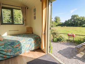 A hut with a bed and a view of the outdoor area at The Three Spaniels Shepherds Hut Cwrtnewydd near Llanybydder