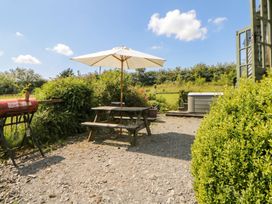 A picnic table with umbrella and hot tub at The Three Spaniels Shepherds Hut Cwrtnewydd near Llanybydder