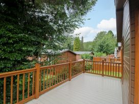 An outdoor deck with wooden railing and view of surrounding cabins at Fox Red Retreat Troutbeck Bridge