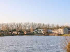 A view of lodges and a building near a lake at Hedgehog Lodge in Carnforth