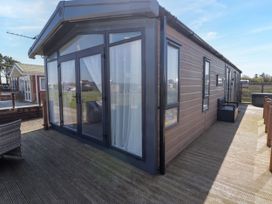 An outdoor area with decking and glass doors at Stone Crab Lodge in Haverfordwest